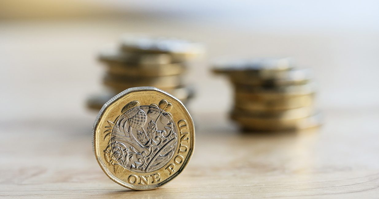 New british one sterling pound coin wiith blurry row stack coins background, Close up British one pound on wooden table Macro studio shot against bright light black background