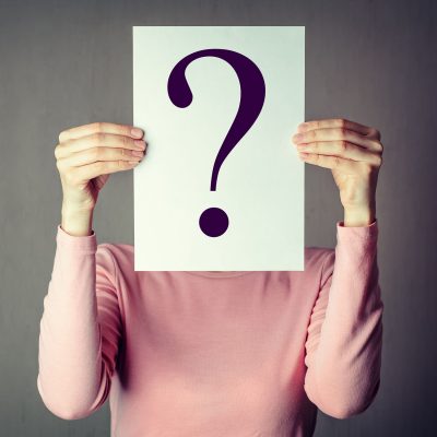 portrait of casual anonymous woman covering face with paper showing question mark.